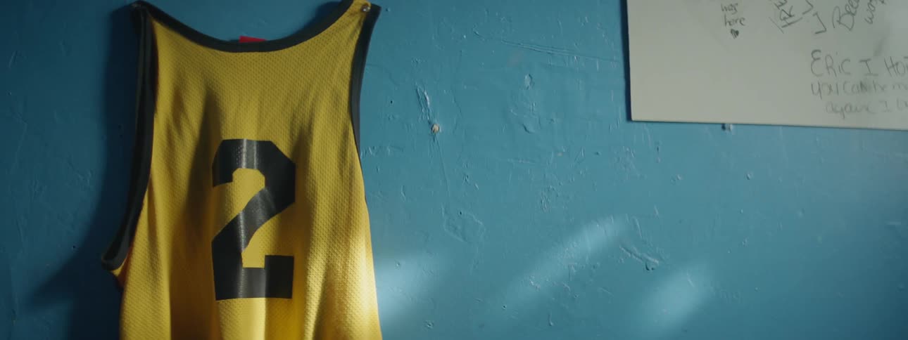 A yellow jersey hangs on a blue wall