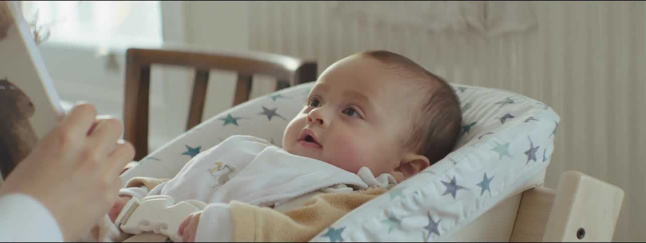 Mother shows book to her ethnically ambiguous baby, the baby is excited to see the book