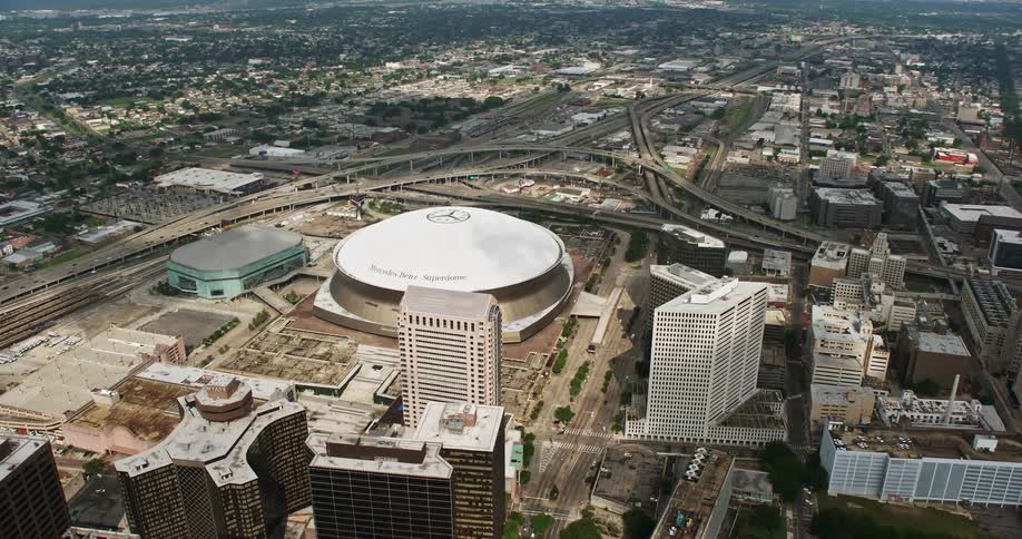 A stunning 4K aerial view of the Mercedes Benz Superdome and New Orleans Arena in Downtown New Orleans during a partly cloudy summer day