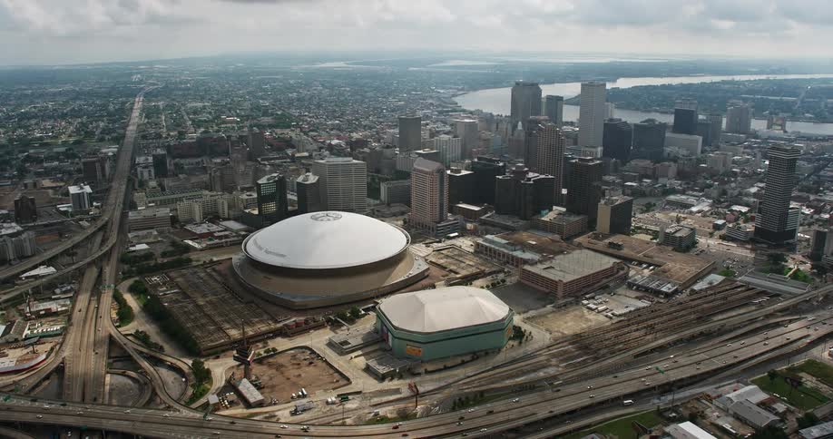 Aerial footage orbiting above the Superdome New Orleans Arena and downtown skyscrapers while showcasing the citys metropolis and recreation areas during the summer