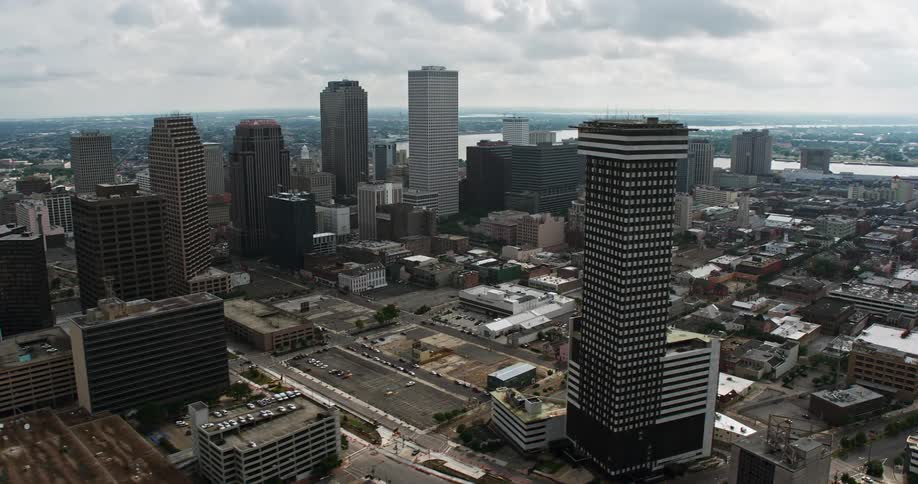 Aerial tilt from freeway interchange reveals Superdome and downtown New Orleans on a cloudy day