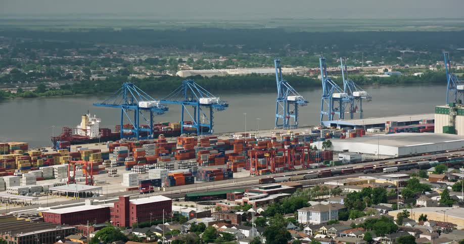 An aerial view of cranes and containers orbiting around the Port of New Orleans while a cargo ship is being unloaded
