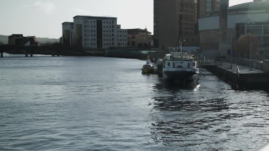 A boat is parked at a harbor next to a small city