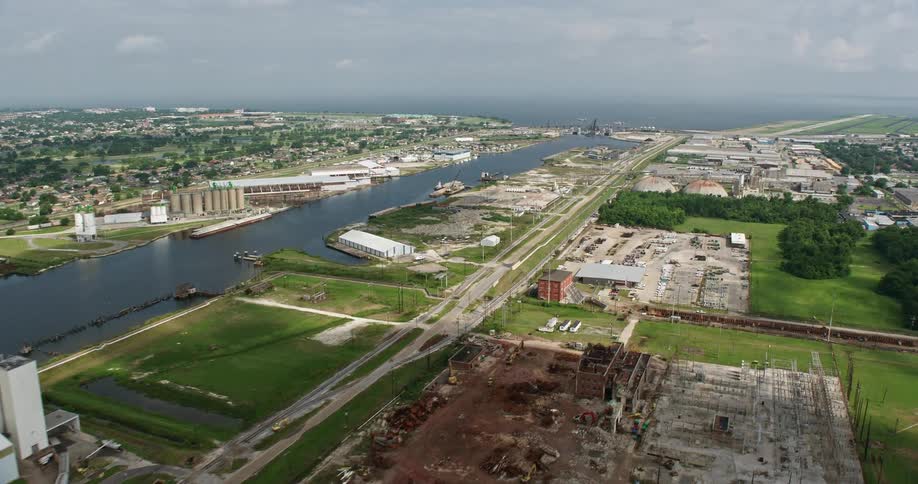 An aerial view of small bridge and factory buildings on the shore of Industrial Canal in New Orleans East Louisiana during a partly cloudy day