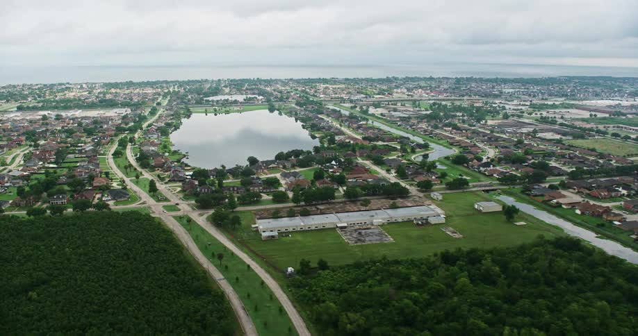 A 4K aerial footage showcasing suburban homes orbiting a small lake during sunrise in New Orleans East Louisiana