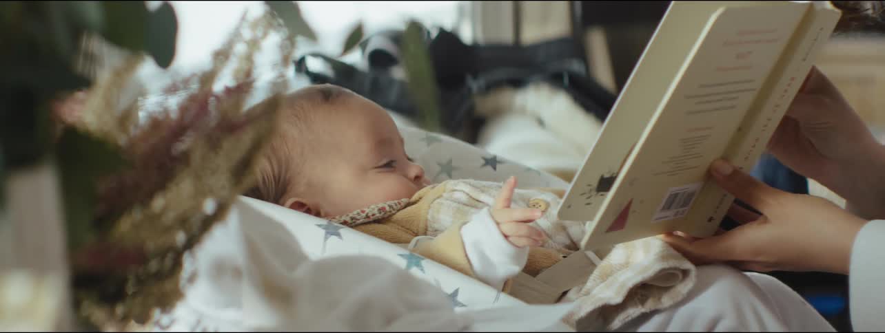 Mother teaching her baby how to turn pages of a book