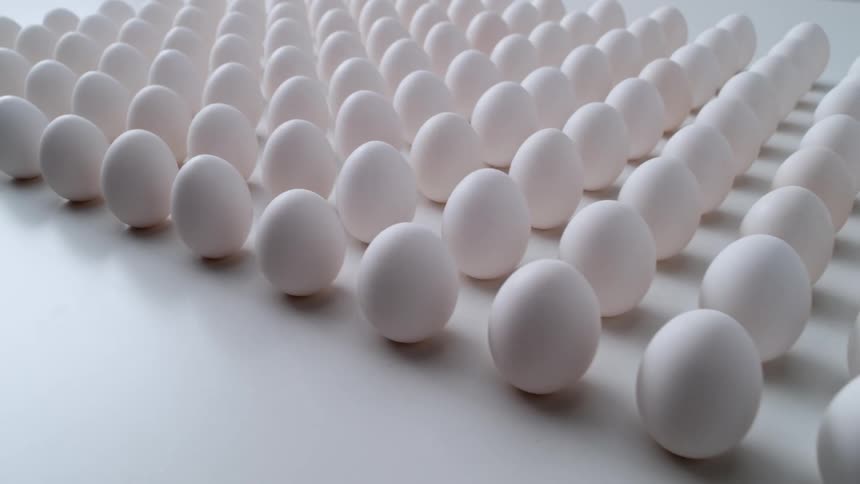 A bunch of eggs have been stood on end and arranged in a square against a white background