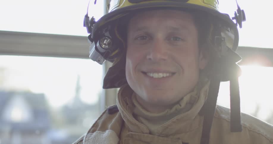 A fireman is suited up and smiling