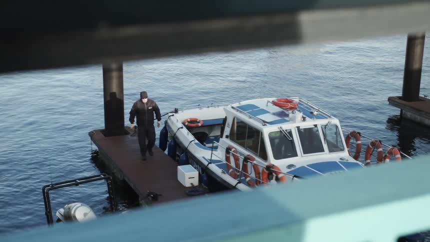 A man finishes securing a boat line then walks away up the dock