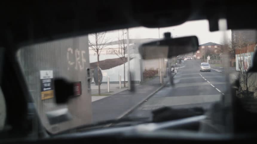 A vehicle on the left hand side of the road is driving through an urban area