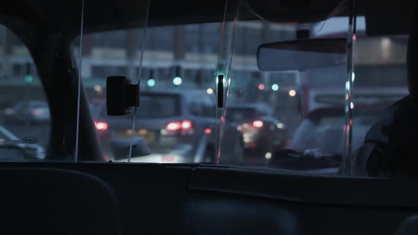 Traffic and lights come into focus through the backseat windshield of a taxi