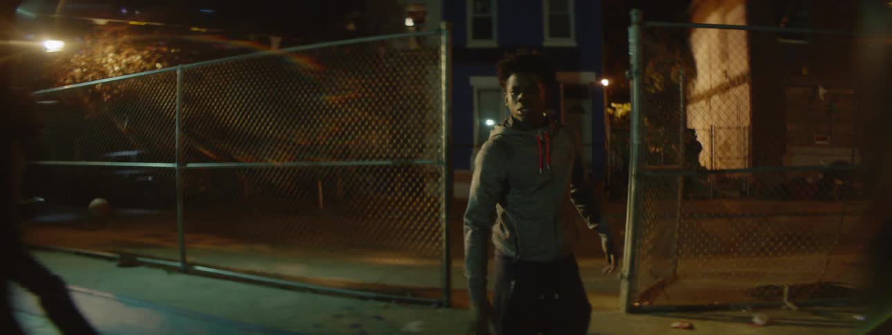 Two men run into a basketball court at night as two men run out