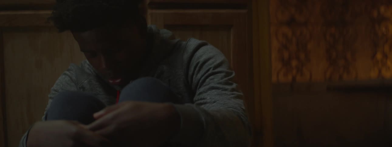 A boy is breathing hard and hugging his knees