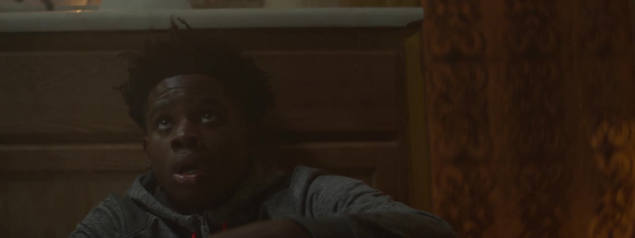 A boy in a hoodie looks up at someone walking by