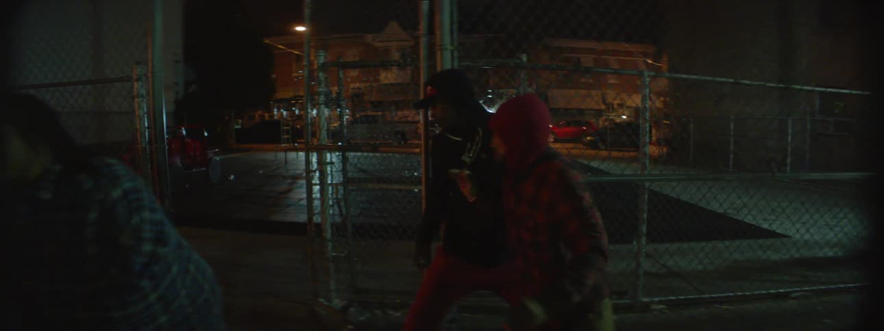 A group of men stand talking then run away in the city at night