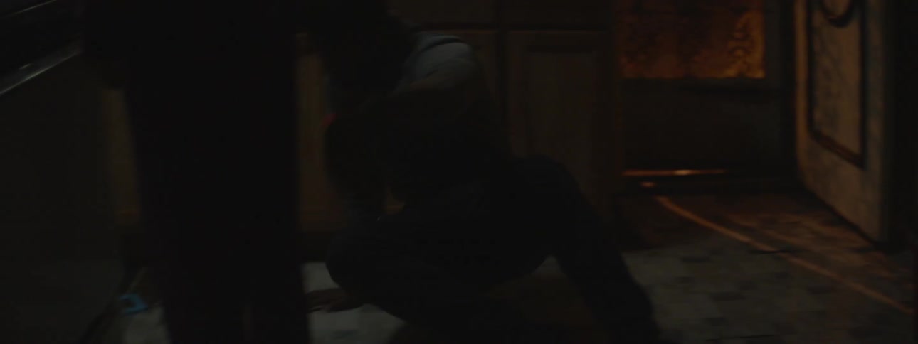 A man jumps into a room and hides behind a cabinet