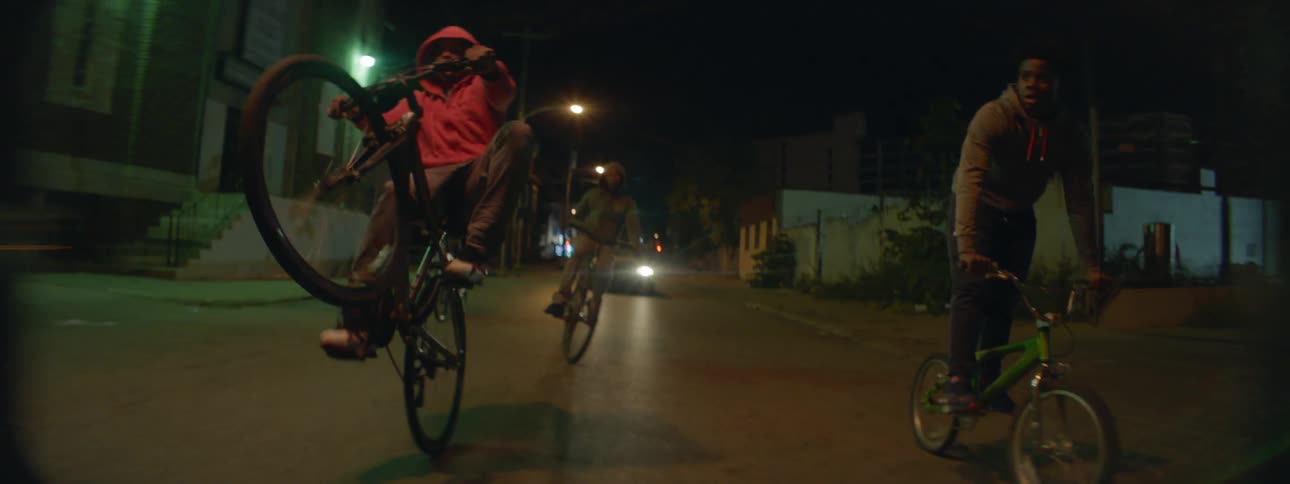 Group of boys riding their bikes down a street at night