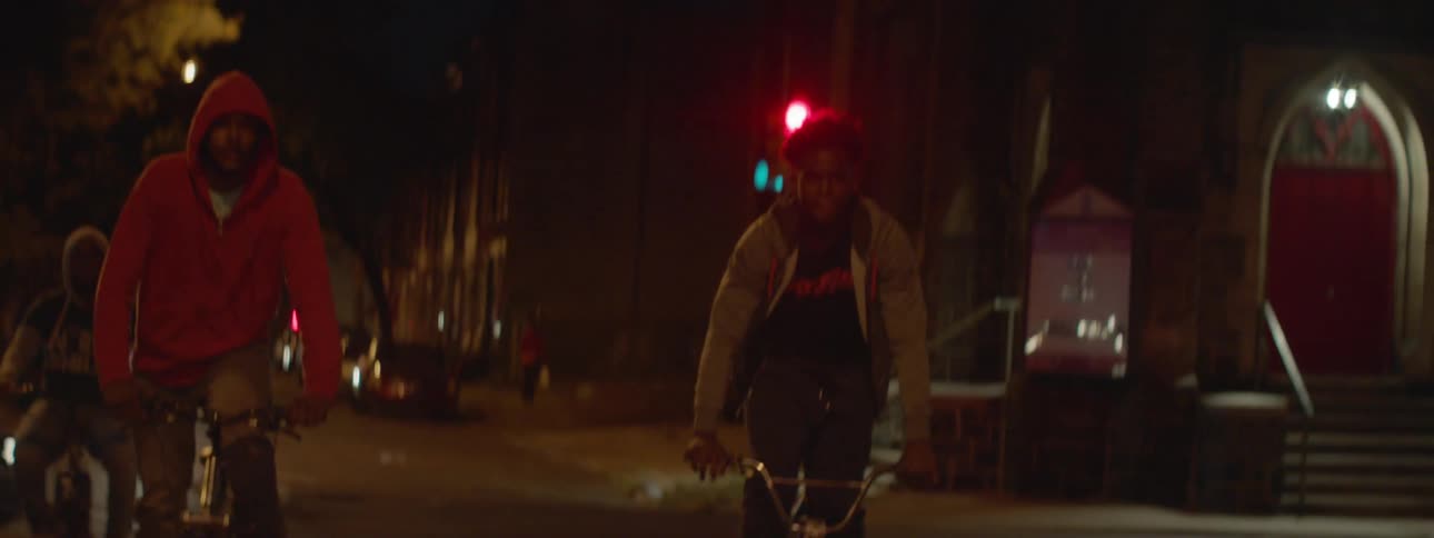 A group of boys ride their bike through the street