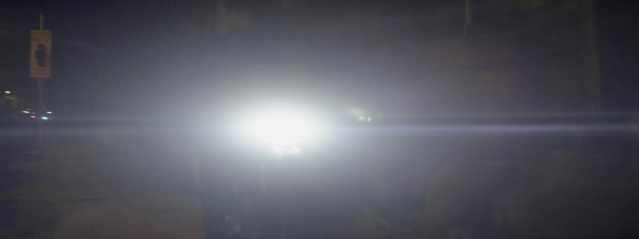 A person rides a motorcycle through a dark alley