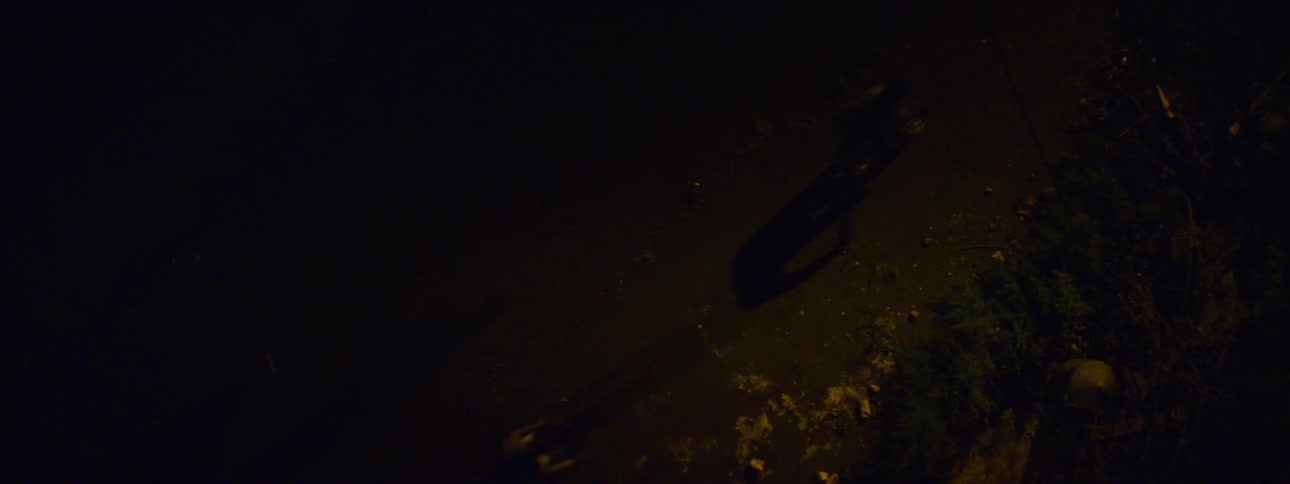 Aerial view of bikers riding down a dirty street in the dark