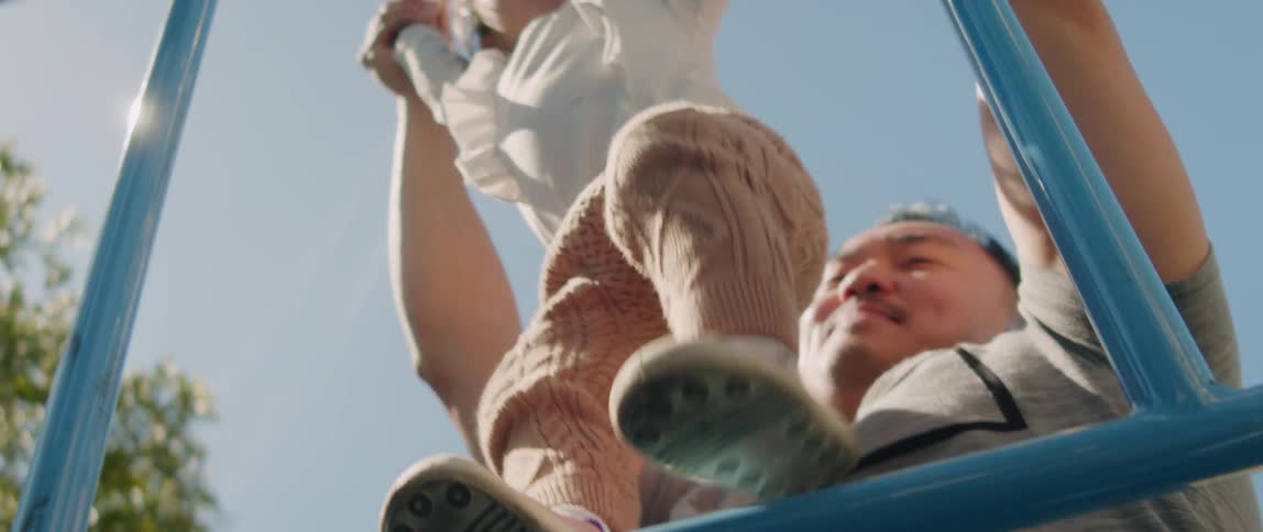 A father helps his daughter climb in the playground