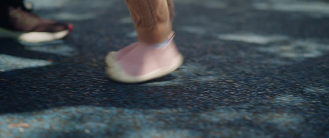 Close up of the pink shoes of a toddler walking in the park at daytime