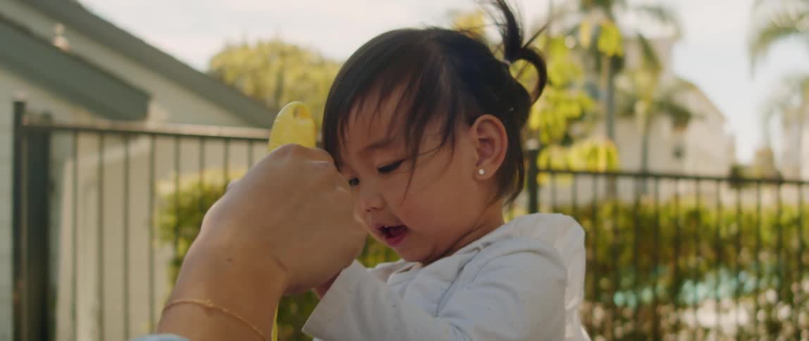 Mother teaches her daughter how to play with a bubble wand in the backyard