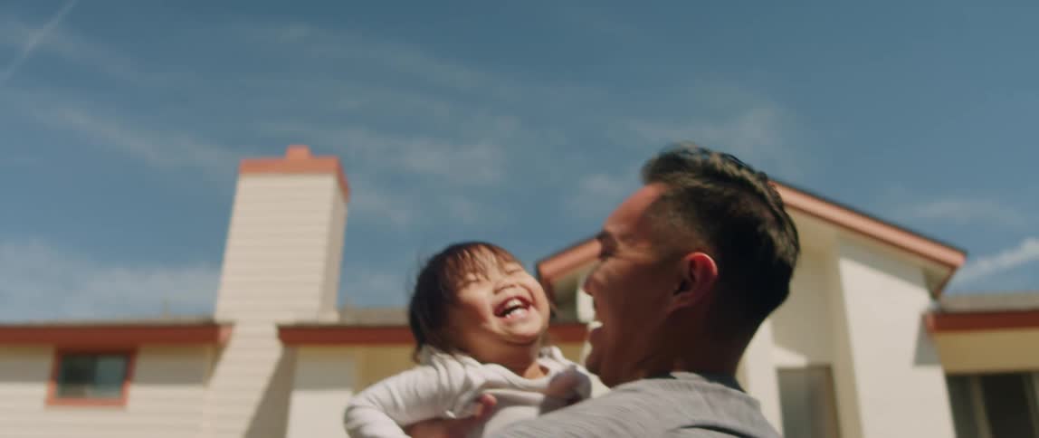 Father playing with toddler daughter outside throwing her up into the air while both are laughing and smiling