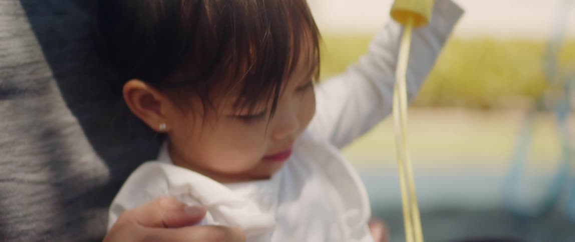 A father holds his daughter close and blows on bubble toy she is holding