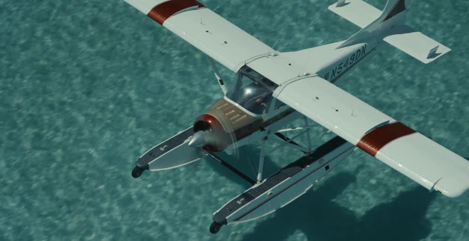 Seaplane with pontoons skims across aquamarine water