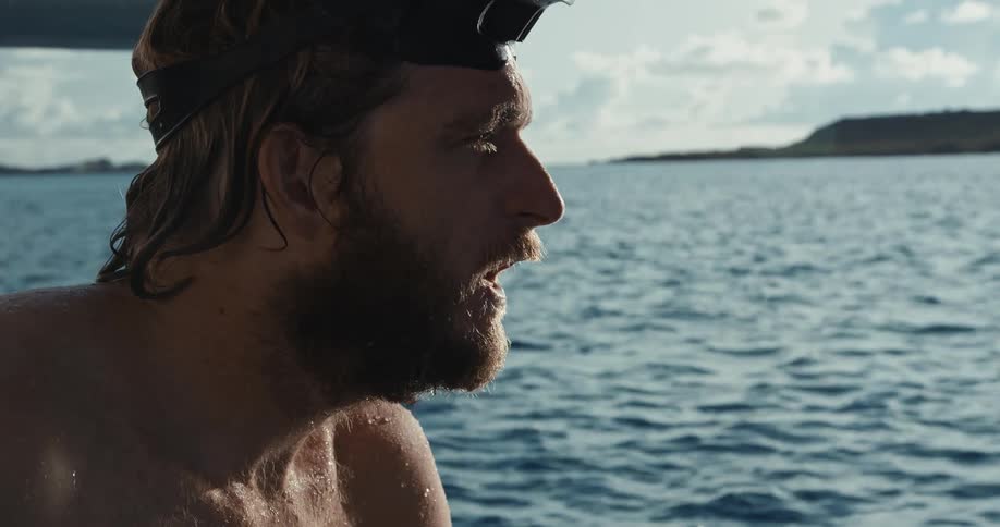 A man is swimming in the ocean water at midday