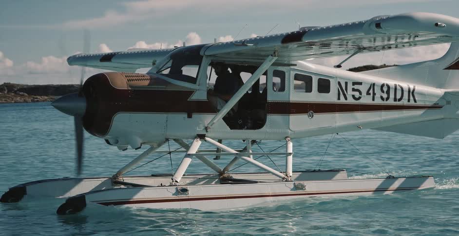 A water plane moving across the water as the pilot sits inside and the propeller turns