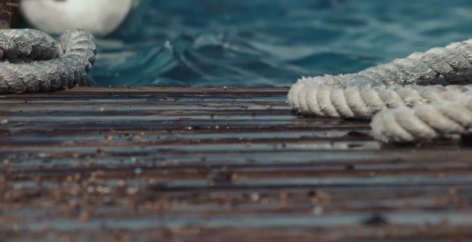 White thick rope laying on wood dock at lakeside