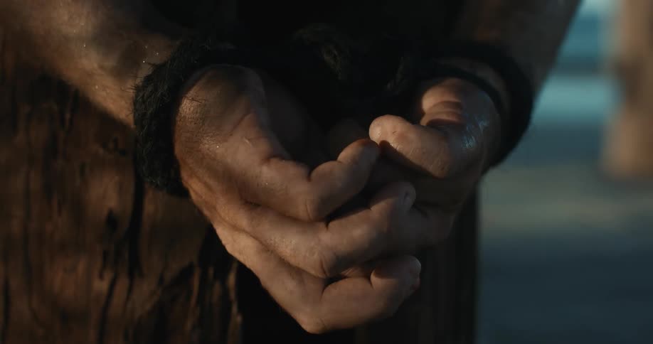 A man with his hands tied behind his back standing still