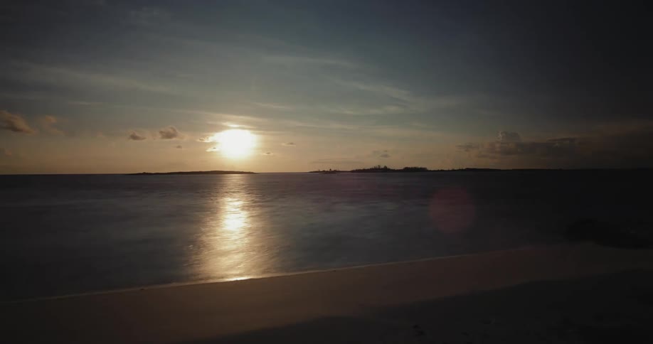 The sun sets over a sandy coastline