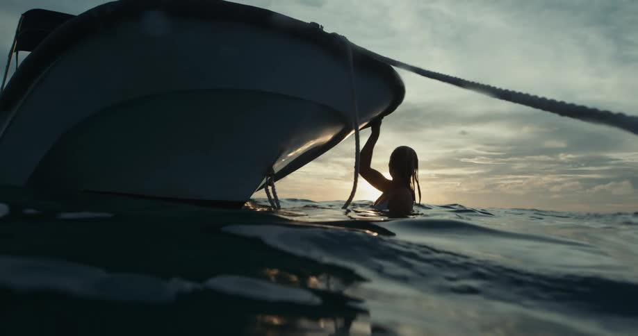 A woman is swimming in the ocean near a boat