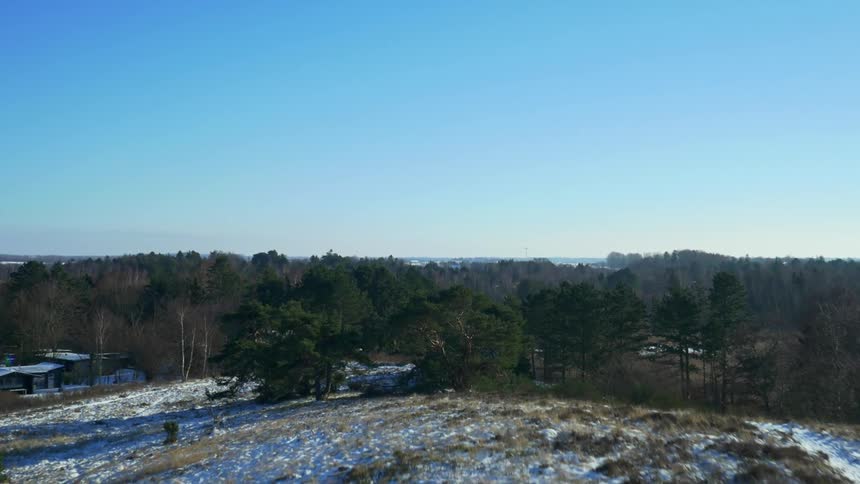 Aerial view of small houses and cabins in the woods of a rural area under the blue sky at winter