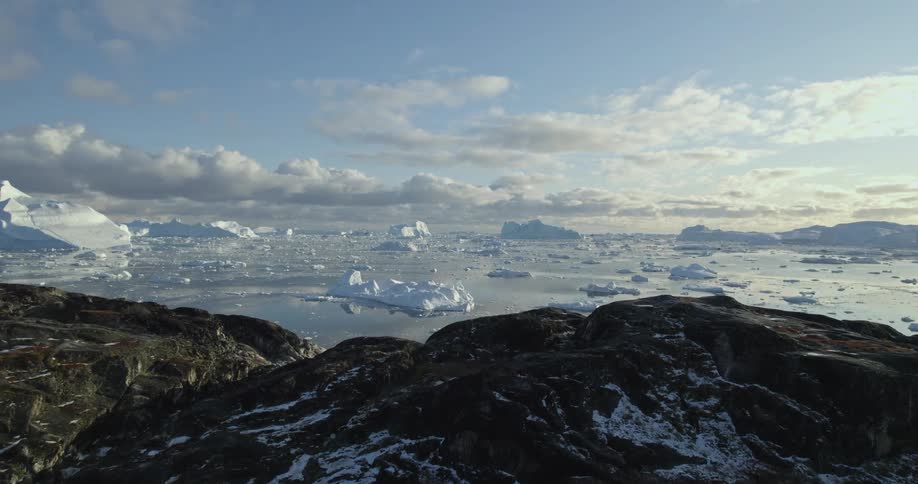 The tip of a mountain revealing waters with icebergs and ice chunks in them