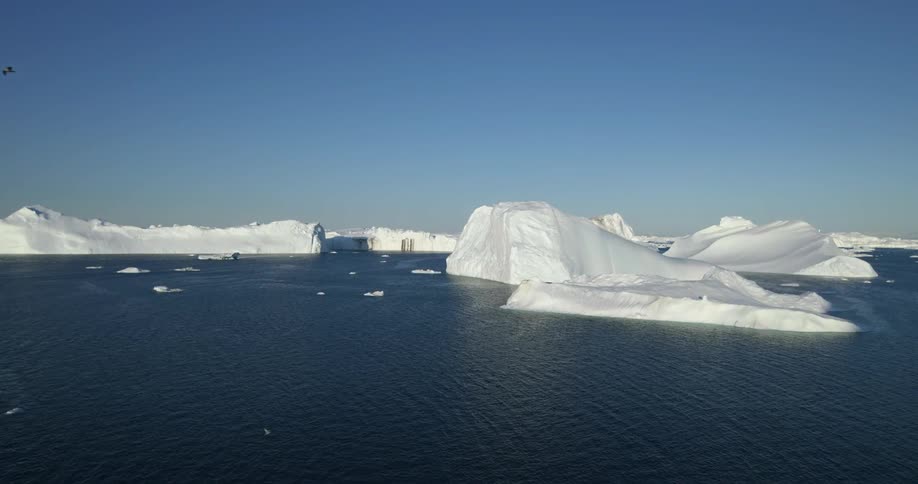 Aerial view of large glaciers floating in the arctic ocean at daytime under a blue sky
