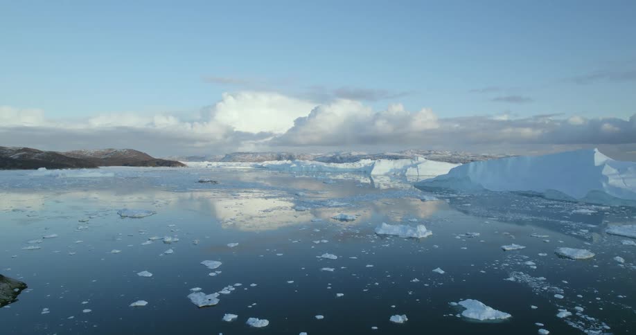 Aerial of icebergs in the artic under blue sky with clouds