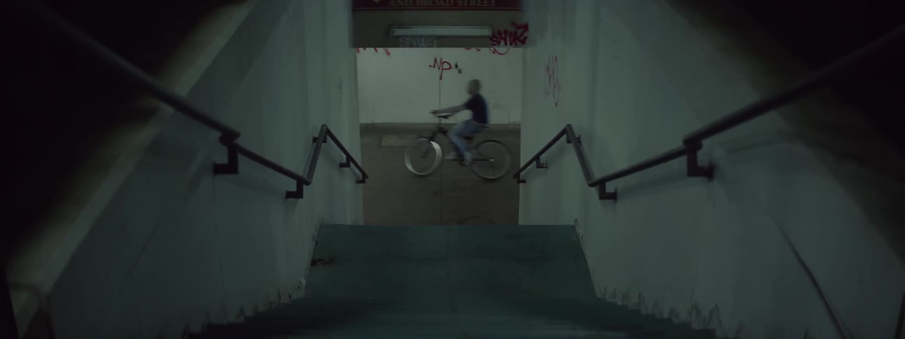 A group of boys on bikes ride past a stairwell