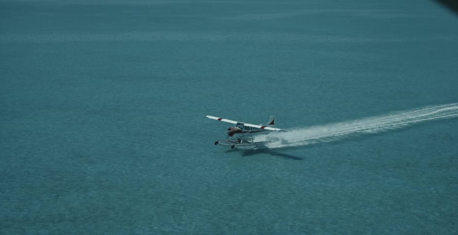 Aerial view of a hydroplane taking off from the clear shallow ocean waters