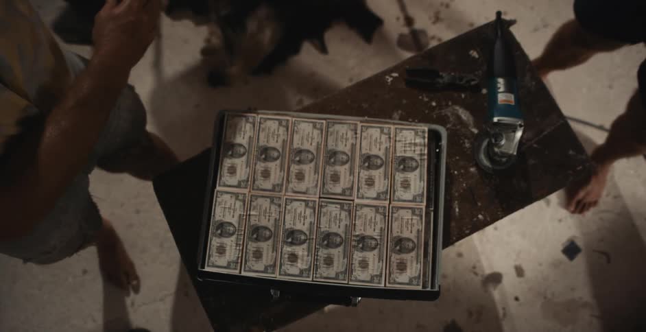A person opening a box with money in it that sits on a table