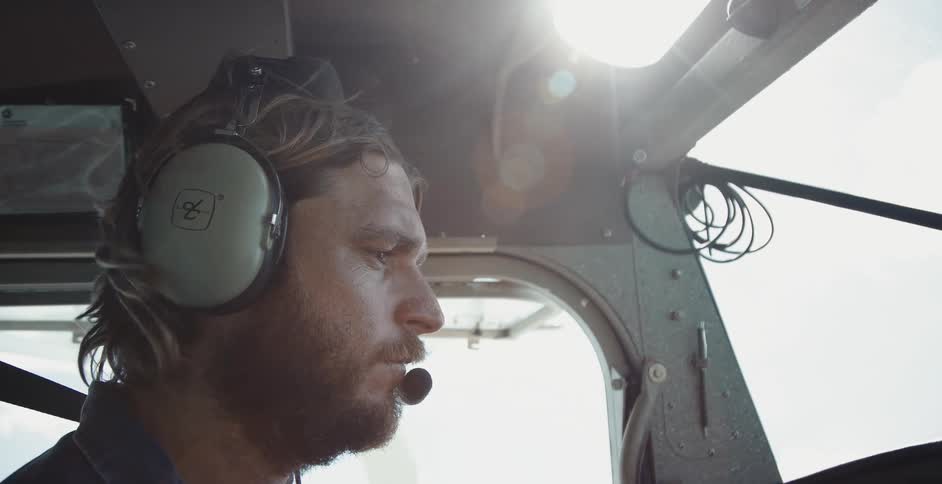 Man wearing a headset in the cockpit piloting a seaplane