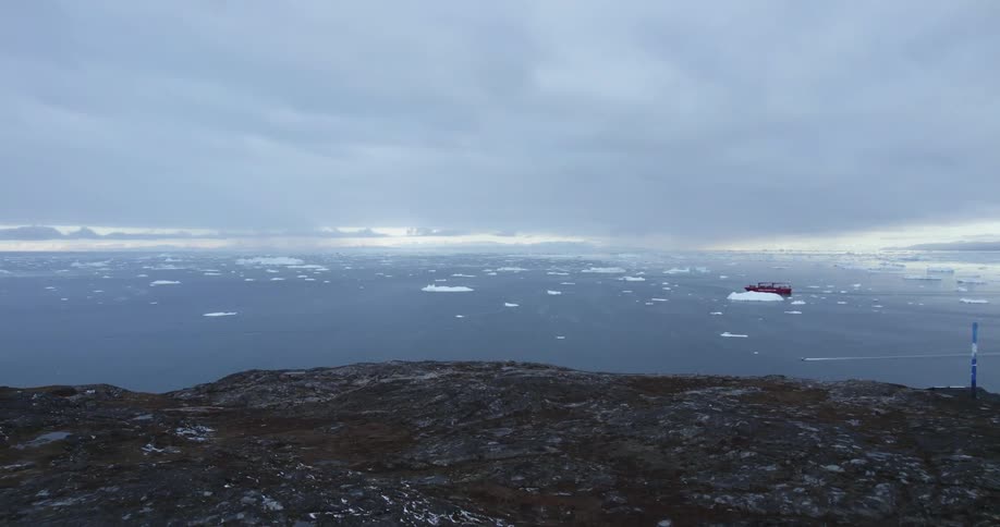 Aerial view of icy ocean with an oil tanker coming over land