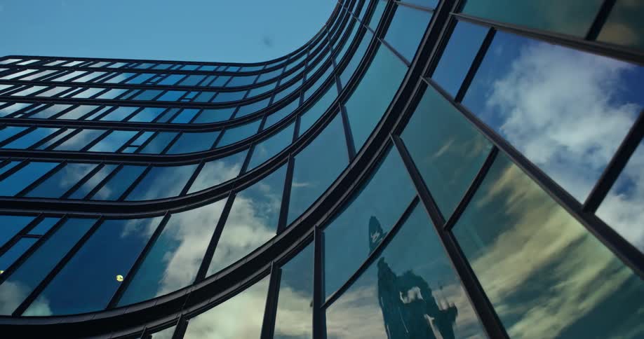 A vertical shot of the big glass wall of an architectural building in a city