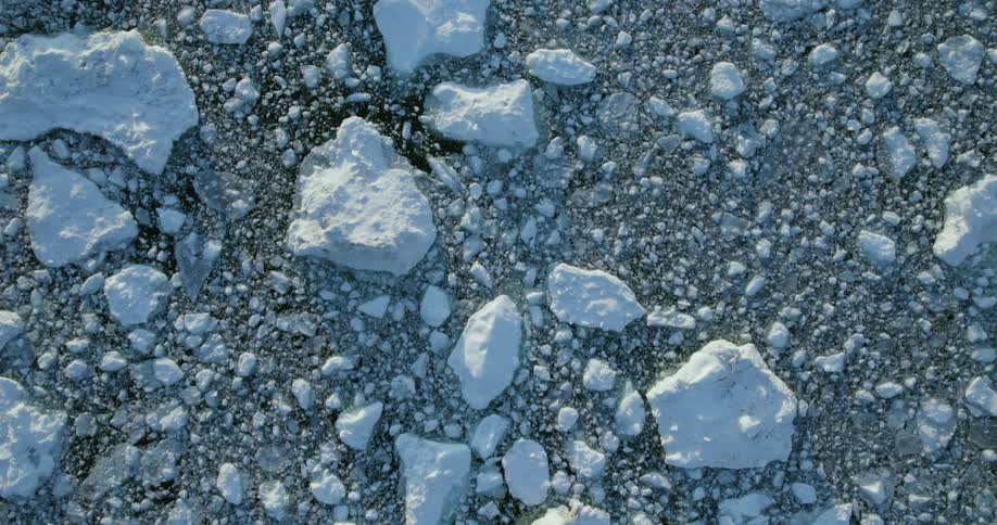Top down aerial view of ice floating in the arctic ocean at evening