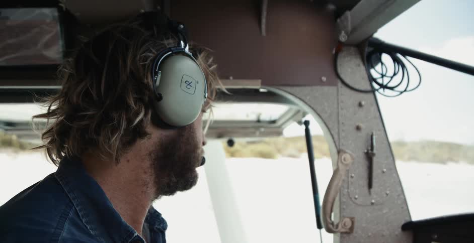 Pilot wearing headset sits in aircraft sitting on surface and looks around