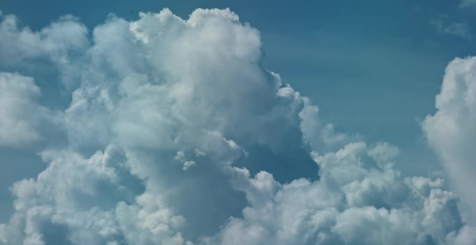 Fluffy cumulus clouds float in a blue sky