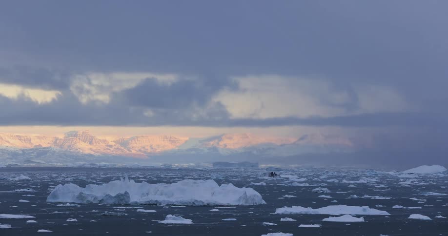 A time lapse of glaciers and icebergs on the ocean with a boat far out onto the ocean
